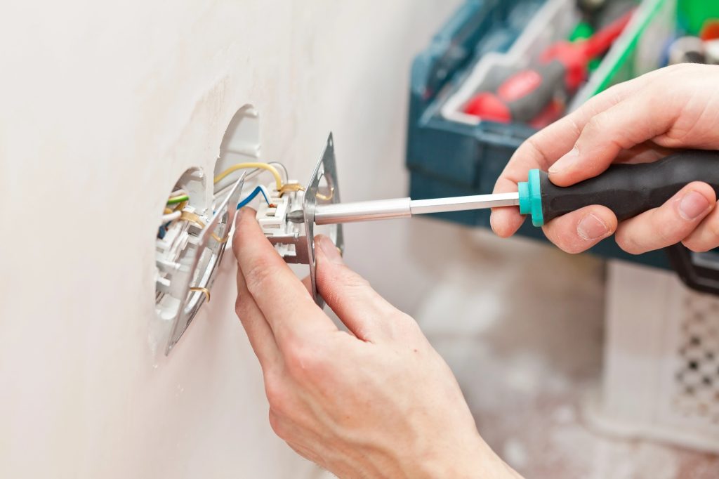 electrician repairing an outlet, know when to call an electrician