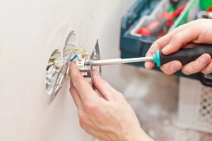 electrician repairing an outlet, know when to call an electrician